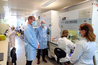 Britain's Prince William, Duke of Cambridge (2L), wearing PPE (personal protective equipment), of a face mask or covering, eye protection and an overall as a precautionary measure against spreading COVID-19, meets scientists including Christina Dold (R) during a visit to the manufacturing laboratory where a vaccine against the novel coronavirus COVID-19 has been produced at the Oxford Vaccine Group's facility at the Churchill Hospital in Oxford, west of London on June 24, 2020, during a visit to learn more about their work to establish a viable vaccine against coronavirus. (Photo by Steve Parsons / POOL / AFP) (Photo by STEVE PARSONS/POOL/AFP via Getty Images)