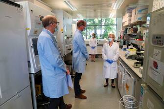 Britain's Prince William, Duke of Cambridge (C), wearing PPE (personal protective equipment), of a face mask or covering, eye protection and an overall, as a precautionary measure against spreading COVID-19, meets scientists during a visit to the manufacturing laboratory where a vaccine against the novel coronavirus COVID-19 has been produced at the Oxford Vaccine Group's facility at the Churchill Hospital in Oxford, west of London on June 24, 2020, during a visit to learn more about their work to establish a viable vaccine against coronavirus. (Photo by Steve Parsons / POOL / AFP) (Photo by STEVE PARSONS/POOL/AFP via Getty Images)