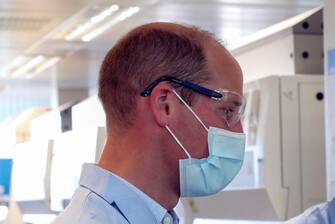 Britain's Prince William, Duke of Cambridge, wearing PPE (personal protective equipment), of a face mask or covering, eye protection and an overall, as a precautionary measure against spreading COVID-19, meets scientists during a visit to the manufacturing laboratory where a vaccine against the novel coronavirus COVID-19 has been produced at the Oxford Vaccine Group's facility at the Churchill Hospital in Oxford, west of London on June 24, 2020, during a visit to learn more about their work to establish a viable vaccine against coronavirus. (Photo by Steve Parsons / POOL / AFP) (Photo by STEVE PARSONS/POOL/AFP via Getty Images)