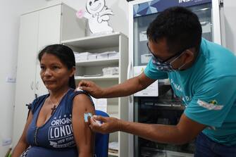 An indigenous woman of the Ticuna ethnic group receives a vaccine at a health post in the Umariacu village, Tabatinga, Amazonas state, Brazil, on June 19, 2020, amid the new coronavirus pandemic. - As the new coronavirus has ravaged Brazil, more than 7,000 indigenous people have contracted the virus, and more than 300 have died, according to the Brazilian Indigenous Peoples' Association (APIB), forcing many indigenous groups to take matters into their own hands. Some have locked the world out, banning outsiders and putting up a makeshift roadblock at the entrance to their territory, while others have fled into the jungle. (Photo by EVARISTO SA / AFP) (Photo by EVARISTO SA/AFP via Getty Images)