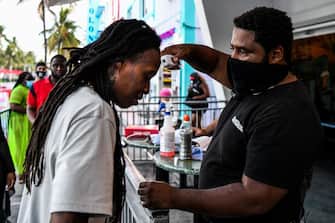 A security guard checks the temperature of a man at the entrance of a restaurant on Ocean Drive in Miami Beach, Florida on June 24, 2020. - With coronavirus cases surging across the US South and West, officials are once again imposing tough measures, from stay-at-home advice in worst-hit states to quarantines to protect recovering areas like New York. Nearly half of the 50 US states have seen an increase in infections over the past two weeks, with some -- such as Texas and Florida -- posting daily records. (Photo by CHANDAN KHANNA / AFP) (Photo by CHANDAN KHANNA/AFP via Getty Images)