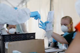 TAMPA, FL - JUNE 25: A healthcare worker hands off a coronavirus testing sample for processing at the Lee Davis Community Resource Center on June 25, 2020 in Tampa, Florida. The USF Health system partnered with the Hillsborough County Government to provide coronavirus testing at several location sites throughout the county. Florida is currently experiencing a surge in COVID-19 cases, as the state reached a new record for single-day infections on Wednesday with 5,511 new cases. (Photo by Octavio Jones/Getty Images)