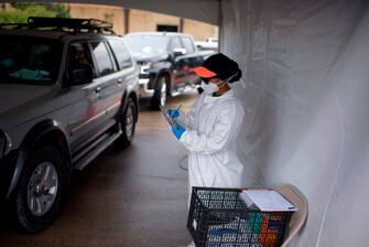 A healthcare worker gets information from people in line at United Memorial Medical Center Covid-19 testing site in Houston, Texas, June 25, 2020. - The United States on June 25 battled a resurgence of coronavirus cases in a number of states including Texas, while the World Health Organization warned that several European countries were also facing dangerous upticks. (Photo by Mark Felix / AFP) (Photo by MARK FELIX/AFP /AFP via Getty Images)