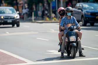NEW YORK, NEW YORK - JUNE 26: People wearing masks ride a moped as the city moves into Phase 2 of re-opening following restrictions imposed to curb the coronavirus pandemic on June 26, 2020 in New York City. Phase 2 permits the reopening of offices, in-store retail, outdoor dining, barbers and beauty parlors and numerous other businesses. Phase 2 is the second of four-phased stages designated by the state.  (Photo by Alexi Rosenfeld/Getty Images)
