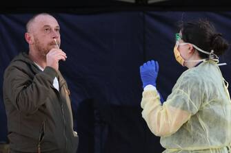 MELBOURNE, AUSTRALIA - JUNE 28: A man places a swab into his nose under the guidance of a member of the Covid-19 testing team at a pop-up facility during a COVID-19 testing blitz in the suburb of Broadmeadows on June 28, 2020 in Melbourne, Australia. Victoria's confirmed COVID-19 infection numbers continue to rise, with 49 new coronavirus cases recorded overnight. Health authorities are continuing on a testing blitz in Melbourne suburbs that have been identified as community transmission hotspots for coronavirus. Restrictions in Victoria have been tightened in response to the spike in new cases across the state with premier Daniel Andrews extending the current state of emergency for at least four weeks to allow police the power to enforce social distancing rules. (Photo by Asanka Ratnayake/Getty Images)