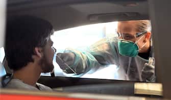 1223424716 A member of the Australian Defence Force takes a swab for a COVID-19 coronavirus test from a member of the public at a drive-through testing station in Melbourne on June 29, 2020. - The nation's second-biggest city, Melbourne, has seen a surge in COVID-19 cases over the past week, with another 75 reported in the last 24 hours. (Photo by William WEST / AFP) (Photo by WILLIAM WEST/AFP via Getty Images)