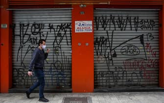 SAO PAULO, BRAZIL - JUNE 29: A man wearing a face mask walks in front of a shuttered shop with a 'For Lease' sign in downtown amidst the coronavirus (COVID-19) pandemic on June 29, 2020 in Sao Paulo, Brazil. Many businesses in the city of Sao Paulo went bankrupt and some commercial spaces are either for sale or for lease during the coronavirus (COVID-19) pandemic.  (Photo by Alexandre Schneider/Getty Images)