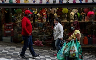 1223466434 SAO PAULO, BRAZIL - JUNE 29: People wearing face masks walk in front of a shop in downtown amidst the coronavirus (COVID-19) pandemic on June 29, 2020 in Sao Paulo, Brazil. The city of Sao Paulo moves to the Yellow phase of quarantine easing, in which commercial establishments can operate following distance rules such as reduced opening hours, restricting the flow of people and maintaining hygiene standards. (Photo by Alexandre Schneider/Getty Images)