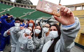 epa08516386 Health workers pose for selfies as they celebrate the end of activities inside the Campaign Hospital of the Pacaembu stadium, in Sao Paulo, Brazil, 29 June 2020. Sao Paulo, the epicenter of COVID-19 in Brazil, closes the Pacaembu stadium field hospital thanks to the slowdown in cases in the city, in contrast to the towns in the interior of the country, where the pathogen is advancing.  EPA/Sebastiao Moreira