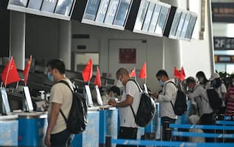 1214791947 Passengers wearing face masks are seen at airline counters at Tianhe airport in Wuhan, in Chinas central Hubei province on May 23, 2020. - China took the rare move of not setting an annual growth target this year after the coronavirus battered the world's second-largest economy and ravaged global growth, Premier Li Keqiang said on May 22. (Photo by Hector RETAMAL / AFP) (Photo by HECTOR RETAMAL/AFP via Getty Images)
