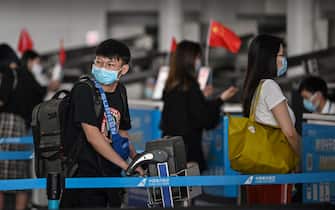 1214791941 Passengers wearing face masks wait in line at an airline counter at Tianhe Airport in Wuhan, in Chinas central Hubei province on May 23, 2020. - China took the rare move of not setting an annual growth target this year after the coronavirus battered the world's second-largest economy and ravaged global growth, Premier Li Keqiang said on May 22. (Photo by Hector RETAMAL / AFP) (Photo by HECTOR RETAMAL/AFP via Getty Images)