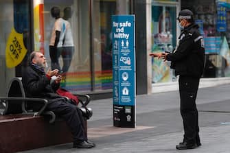 1253629772 LEICESTER, ENGLAND - JULY 01: A police officer talks to a man sitting on a bench during lockdown on July 01, 2020 in Leicester, England. Ten per cent of all the recent UKs Covid-19 deaths occurred in Leicester, which became the first British city to be put into regional lockdown on Tuesday night. (Photo by Darren Staples/Getty Images)