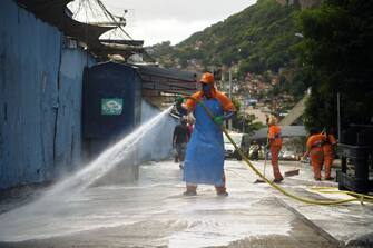 A municipal worker disinfects an area outside Rocinha favela in Rio de Janeiro, Brazil as a preventive measure against the spread of the COVID-19 coronavirus on April 9, 2020. - Brazil's health minister said Wednesday that authorities should hold talks with drug gangs and militia groups in impoverished favela neighborhoods on how to contain the new coronavirus. (Photo by CARL DE SOUZA / AFP) (Photo by CARL DE SOUZA/AFP via Getty Images)