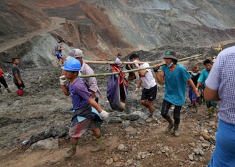 epa08522659 Volunteers carry the body of a victim after a landslide at a jade mining site in Hpakant, Kachin State, Myanmar, 02 July 2020. According to media reports, search and rescue efforts are ongoing after a landslide at a jade mining site was triggered by heavy rain. At least 126 bodies have been found, media added.  EPA/ZAW MOE HTET