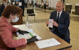 TOPSHOT - Russian President Vladimir Putin shows his passport to a member of a local electoral commission as he arrives to cast his ballot in a nationwide vote on constitutional reforms at a polling station in Moscow on July 1, 2020. (Photo by Alexei Druzhinin / SPUTNIK / AFP) (Photo by ALEXEI DRUZHININ/SPUTNIK/AFP via Getty Images)