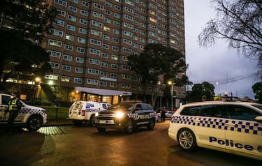 MELBOURNE, AUSTRALIA - JULY 04: Police cars surround the housing commission flats in the suburb of Flemington, where a coronavirus outbreak has been recorded, on July 04, 2020 in Melbourne, Australia. Lockdowns across Melbourne are in effect for residents of suburbs identified as COVID-19 hotspots following a spike in new coronavirus cases through community transmission. Residents of the 10 Melbourne hotspot postcodes are only able to leave home for exercise or work, to buy essential items including food or to access childcare and healthcare. Businesses and facilities in these lockdown areas are also restricted and cafes and restaurants can only open for takeaway and delivery. The restrictions will remain in place until at least 29 July.  (Photo by Asanka Ratnayake/Getty Images)