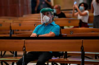 A man wearing a face mask sits at the Sagrada Familia basilica in Barcelona on July 4, 2020 as it reopens with a tribute to healthcare workers following a national lockdown to stop the spread of the novel coronavirus. (Photo by Josep LAGO / AFP) (Photo by JOSEP LAGO/AFP via Getty Images)