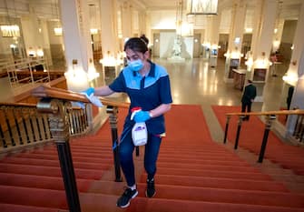 A woman disinfects a hand rail of a stairway between concerts at the 'Wiener Konzerthaus' in Vienna, Austria on June 6, 2020. - Concert houses in Vienna reopened their doors this weekend for limited audiences after being completely closed due to the new coronavirus lockdown" (Photo by JOE KLAMAR / AFP) (Photo by JOE KLAMAR/AFP via Getty Images)