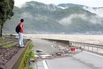 epa08525910 A man looks at the river Kuma overflowing in Yatsushiro, Kumamoto prefecture, southwestern Japan, 04 July 2020. Local authorities asked the evacuation of more than 200,000 residents in Japan's southwestern prefectures of Kumamoto and Kagoshima following floods and mudslides triggered by torrential rain.  EPA/JIJI PRESS JAPAN OUT EDITORIAL USE ONLY/  NO ARCHIVES