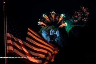 A US flag flies as fireworks explode above the Mount Rushmore National Monument during an Independence Day event attended by the US president in Keystone, South Dakota, July 3, 2020. (Photo by ANDREW CABALLERO-REYNOLDS / AFP) (Photo by ANDREW CABALLERO-REYNOLDS/AFP via Getty Images)