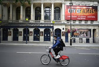 epa08530565 A masked cyclist passes the Garrick theatre in the West End of London, Britain, 06 July 2020. Britain's government has announced a 1.57bn pounds emergency support package to help protect the futures of theatres, galleries and museum across the country. Many arts institutions are facing financial difficulty due to the ongoing coronavirus pandemic.  EPA/NEIL HALL