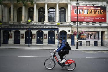 epa08530565 A masked cyclist passes the Garrick theatre in the West End of London, Britain, 06 July 2020. Britain's government has announced a 1.57bn pounds emergency support package to help protect the futures of theatres, galleries and museum across the country. Many arts institutions are facing financial difficulty due to the ongoing coronavirus pandemic. EPA/NEIL HALL