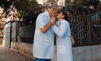Cuban doctor Liz Caballero (R) kisses her husband goodbye before going to work at the polyclinic of Havana's Vedado neighbourhood where she works as a teacher and a doctor, on May 5, 2020 during the COVID-19 coronavirus pandemic. - It is May now as since the new coronavirus arrived in Cuba in March, Caballero has not rested. She takes her students door by door in the neighbourhood in search of new cases, a task she feels is very important. (Photo by Adalberto ROQUE / AFP) (Photo by ADALBERTO ROQUE/AFP via Getty Images)
