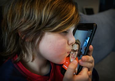 BEIJING, CHINA - MARCH 30: Canadian Jetsun Frayer, 6 years old and son of the photographer, kisses the phone as he talks with his mother journalist Janis Mackey Frayer from a hotel room where he is temporarily staying, as she does the last two days of her Chinese government mandated quarantine alone at their apartment, on March 30, 2020 in Beijing, China. Around the globe, children of all ages are spending more time at home with parents and carers as society attempts to slow the spread of the Coronavirus (COVID-19). The pandemic has claimed over 130,000 lives and infected over 2 million people worldwide. (Photo by Kevin Frayer/Getty Images)
