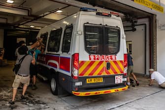 1224460221 HONG KONG, CHINA - JULY 03: Members of media photograph a police van transporting a 24-year-old man who allegedly wounded a policeman with a knife during a protest on July 1 as it enters the Eastern Magistrates' Courts Building on July 03, 2020 in Hong Kong, China. (Photo by Billy H.C. Kwok/Getty Images)