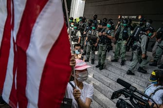 1224648471 HONG KONG, CHINA - JULY 04: Riot police deter a woman as she display a US flag to celebrate the declaration of Independence of the United States outside the US Consulate General on July 4, 2020 in Hong Kong, China. Hong Kong marked the 23rd anniversary of the handover of the former British colony to China on July 1 hours after Beijing imposed the new national security law. (Photo by Anthony Kwan/Getty Images)