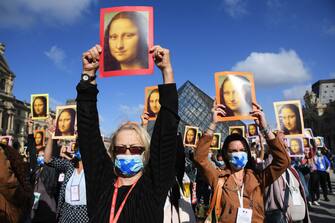 PARIS, FRANCE - JULY 06: Visitors hold reproductions of the Mona Lisa outside the Louvre museum as it reopens its doors following its 16 week closure due to lockdown measures caused by the COVID-19 coronavirus pandemic, at the Louvre on July 6, 2020 in Paris, France. (Photo by Pascal Le Segretain/Getty Images)