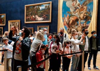 Visitors wearing face masks take pictures in front of Leonardo da Vinci's masterpiece  " Mona Lisa " also known as " La Gioconda "  held in the Salle des  Etats, at the Louvre Museum in Paris on July 6, 2020, on the museum' s reopening day. - The Louvre museum will reopen its doors on July 6, 2020, after months of closure due to lockdown measures linked to the COVID-19 pandemic, caused by the novel coronavirus. The coronavirus crisis has already caused "more than 40 million euros in losses" at the Louvre, announced its president and director Jean-Luc Martinez, who advocates a revival through "cultural democratization" and is preparing a "transformation plan" for the upcoming Olympic Games in 2024. (Photo by FRANCOIS GUILLOT / AFP) (Photo by FRANCOIS GUILLOT/AFP via Getty Images)