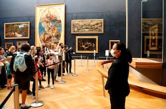 Visitors wearing face masks take pictures in front of Leonardo da Vinci's masterpiece  " Mona Lisa " also known as " La Gioconda "  held in the Salle des  Etats, at the Louvre Museum in Paris on July 6, 2020, on the museum' s reopening day. - The Louvre museum will reopen its doors on July 6, 2020, after months of closure due to lockdown measures linked to the COVID-19 pandemic, caused by the novel coronavirus. The coronavirus crisis has already caused "more than 40 million euros in losses" at the Louvre, announced its president and director Jean-Luc Martinez, who advocates a revival through "cultural democratization" and is preparing a "transformation plan" for the upcoming Olympic Games in 2024. (Photo by FRANCOIS GUILLOT / AFP) (Photo by FRANCOIS GUILLOT/AFP via Getty Images)