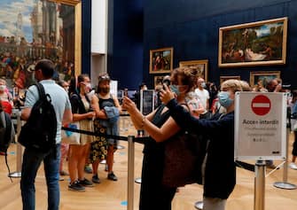 People wearing face masks take pictures as they visit the Louvre Museum in Paris on July 6, 2020, on the museum' s reopening day. - The Louvre museum will reopen its doors on July 6, 2020, after months of closure due to lockdown measures linked to the COVID-19 pandemic, caused by the novel coronavirus. The coronavirus crisis has already caused "more than 40 million euros in losses" at the Louvre, announced its president and director Jean-Luc Martinez, who advocates a revival through "cultural democratization" and is preparing a "transformation plan" for the upcoming Olympic Games in 2024. (Photo by FRANCOIS GUILLOT / AFP) (Photo by FRANCOIS GUILLOT/AFP via Getty Images)