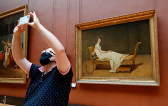 A woman wearing face mask takes a pictures as she visit the Louvre Museum in Paris on July 6, 2020, on the museum' s reopening day. - The Louvre museum will reopen its doors on July 6, 2020, after months of closure due to lockdown measures linked to the COVID-19 pandemic, caused by the novel coronavirus. The coronavirus crisis has already caused "more than 40 million euros in losses" at the Louvre, announced its president and director Jean-Luc Martinez, who advocates a revival through "cultural democratization" and is preparing a "transformation plan" for the upcoming Olympic Games in 2024. (Photo by FRANCOIS GUILLOT / AFP) (Photo by FRANCOIS GUILLOT/AFP via Getty Images)
