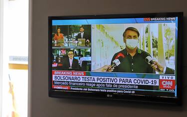 A municipal funeral home worker watches the live news showing Brazilian President Jair Bolsonaro announcing his positive result of the COVID-19 test in Curitiba, Brazil on July 7, 2020. - Brazil President Jair Bolsonaro announced on Tuesday he had tested positive for the coronavirus but said he was feeling "perfectly well" and had only mild symptoms. (Photo by DANIEL CASTELLANO / AFP) (Photo by DANIEL CASTELLANO/AFP via Getty Images)