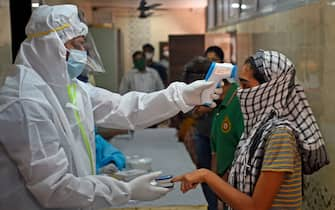 A medical volunteer wearing Personal Protective Equipment (PPE) gear takes temperature reading of a woman during a medical screening for the COVID-19 coronavirus, at a residential society in Mumbai on July 10, 2020. - Hospitals in densely populated cities such as Mumbai and Delhi are struggling to cope with the epidemic, and the country now has around 720,000 infections -- the world's third-highest. (Photo by Punit PARANJPE / AFP) (Photo by PUNIT PARANJPE/AFP via Getty Images)