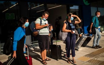 Passengers of a flight from Budapest wearing protective face masks arrive at the Corfu Airport Ioannis Kapodistrias on Corfu Island on July 1, 2020, on its reopening day following months of closure due to the sanitary measures taken to curb the spread of the Covid-19 disease caused by the novel coronavirus. - Greece on July 1, 2020 reopened flights to its flagship island destinations as it raced to salvage a portion of the annual tourism season that is vital to its economy. (Photo by ANGELOS TZORTZINIS / AFP) (Photo by ANGELOS TZORTZINIS/AFP via Getty Images)