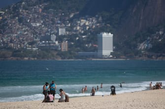 1226592855 RIO DE JANEIRO, BRAZIL - JULY 12: City hall inspectors warn and notify beach goers of new rules at Arpoador Beach amidst the coronavirus (COVID-19) pandemic on July 12, 2020 in Rio de Janeiro, Brazil. The practice of physical activities on boardwalks and individual sports at sea is allowed. However, the use of chairs and tents on the sand is still prohibited. Mayor Marcelo Crivella warned of the intensification of inspection and the imposition of a fine for those who do not comply with the rules. (Photo by Bruna Prado/Getty Images)