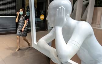 TOPSHOT - A woman wearing a face mask enters a shopping mall, partially closed to combat the spread of the COVID-19 novel coronavirus, in Bangkok on April 7, 2020. - Supermarkets, pharmacies and banks remained open as other commercial business were closed at Bangkok shopping malls due to concerns over coronavirus. (Photo by Mladen ANTONOV / AFP) (Photo by MLADEN ANTONOV/AFP via Getty Images)