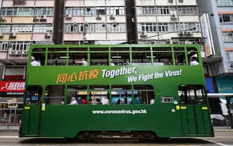 Commuters travel on a tram with a notice that refers to the COVID-19 coronavirus in Hong Kong on July 9, 2020. (Photo by Anthony WALLACE / AFP) (Photo by ANTHONY WALLACE/AFP via Getty Images)