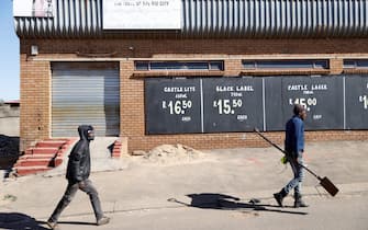 People walk past a closed liquor shop in Soweto, on July 13, 2020. - South African President Cyril Ramaphosa on July 12, 2020 re-imposed a night curfew and suspended alcohol sales as COVID-19 coronavirus infections spiked and the health system risked being overwhelmed. (Photo by Michele Spatari / AFP) (Photo by MICHELE SPATARI/AFP via Getty Images)