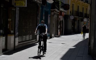 A man wearing a face mask rides a bike in Lerida (Lleida) on July 13, 2020. - A local court suspended a home confinement order imposed on more than 200,000 people in the Spanish region of Catalonia after an upsurge in virus cases. Catalonia officials ordered the home confinement on the city of Lerida and its surrounding areas a week after the zone had been placed under less strict lockdown. (Photo by Pau BARRENA / AFP) (Photo by PAU BARRENA/AFP via Getty Images)