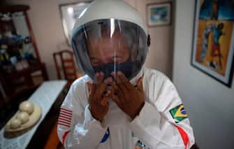 TOPSHOT - Brazilian accountant Tercio Galdino, 66, puts a helmet on as he prepares to go to Copacabana beach in protective suit, in Rio de Janeiro, Brazil on July 12, 2020. - Tercio, who has a chronic lung disease, made protective suits (looking like astronauts gear) for him and his wife at home using suits used by health professionals. He says that, in addition to giving him protection against the new coronavirus, they also wear them for fun, as he has huge interest in astronomy. (Photo by Mauro Pimentel / AFP) (Photo by MAURO PIMENTEL/AFP via Getty Images)