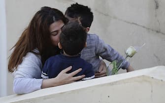 Young boys kiss their mother who just received a rose delivered to her via a drone on Mother's day, in Okaibeh, north of the capital Beirut on March 21, 2020, as people remain indoors in an effort to limit the spread of the novel coronavirus. - In a quiet Lebanese town under lockdown over the novel coronavirus, a drone buzzed towards a balcony on Saturday to deliver a red rose to a mother grinning in surprise. The COVID-19 pandemic may have put a damper on Mother's Day this year, but three students have come up with a novel service to celebrate the occasion without flouting social distancing restrictions. (Photo by JOSEPH EID / AFP) (Photo by JOSEPH EID/AFP via Getty Images)