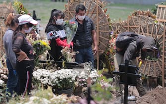 VALLE DE CHALCO, MEXICO - JULY 13: Relatives of a deceased in the last month visit a grave at the San Miguel Xico cementery on July 13, 2020 in Valle de Chalco, Mexico. Mexican Health Secretary announced the country reached 35,006 victims from COVID-19, surpassing Italy but behind US, Brazil and UK. According to Johns Hopkins University, Mexico has registered 299,750 positive cases. Critics say Government started reopening economy too soon and this would increase number of victims. At the beginning of the pandemic, President Lopez Obrador had been accused of downplaying the effects of the virus to protect economic activity.  (Photo by Hector Vivas/Getty Images)