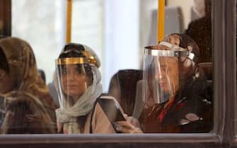 Passengers, wearing face shields due to the COVID-19 coronavirus, sit inside a bus in the Iranian capital Tehran on June 22, 2020. (Photo by ATTA KENARE / AFP) (Photo by ATTA KENARE/AFP via Getty Images)