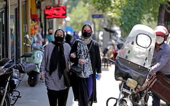 Iranian pedestrians wearing protective masks due to the COVID-19 pandemic, walk along a street in the capital Tehran on July 1, 2020. (Photo by ATTA KENARE / AFP) (Photo by ATTA KENARE/AFP via Getty Images)