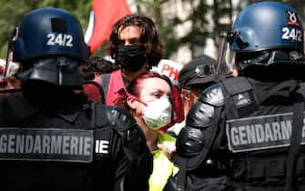 A protester wearing a protective face mask faces French Gendarmes during a demonstration in Paris, on July 14, 2020, as part of a nationwide day of protests by health workers to demand better work conditions. - Health care workers are protesting in France on the country's National day to demand more for their sector a day after the government and unions signed an agreement giving over eight billion euros in pay rises, with the prime minister admitting the move was overdue in view of the coronavirus pandemic. (Photo by Zakaria ABDELKAFI / AFP) (Photo by ZAKARIA ABDELKAFI/AFP via Getty Images)