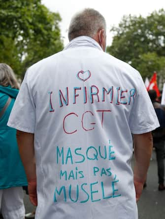 A protester wears a white coat reading "CGT nurse, masked not muselled" during a  demonstration in Paris, on July 14, 2020, as part of a nationwide day of protests by health workers to demand better work conditions. - Health care workers are protesting in France on the country's National day to demand more for their sector a day after the government and unions signed an agreement giving over eight billion euros in pay rises, with the prime minister admitting the move was overdue in view of the coronavirus pandemic. (Photo by Zakaria ABDELKAFI / AFP) (Photo by ZAKARIA ABDELKAFI/AFP via Getty Images)